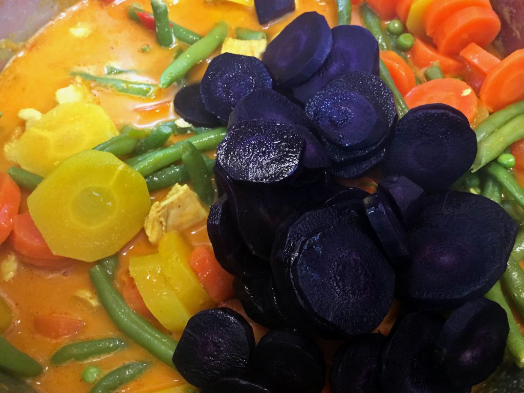 Kokos-Gemüse-Curry mit Hähnchen - lilafarbene, gelbe und organefarbene Karotten